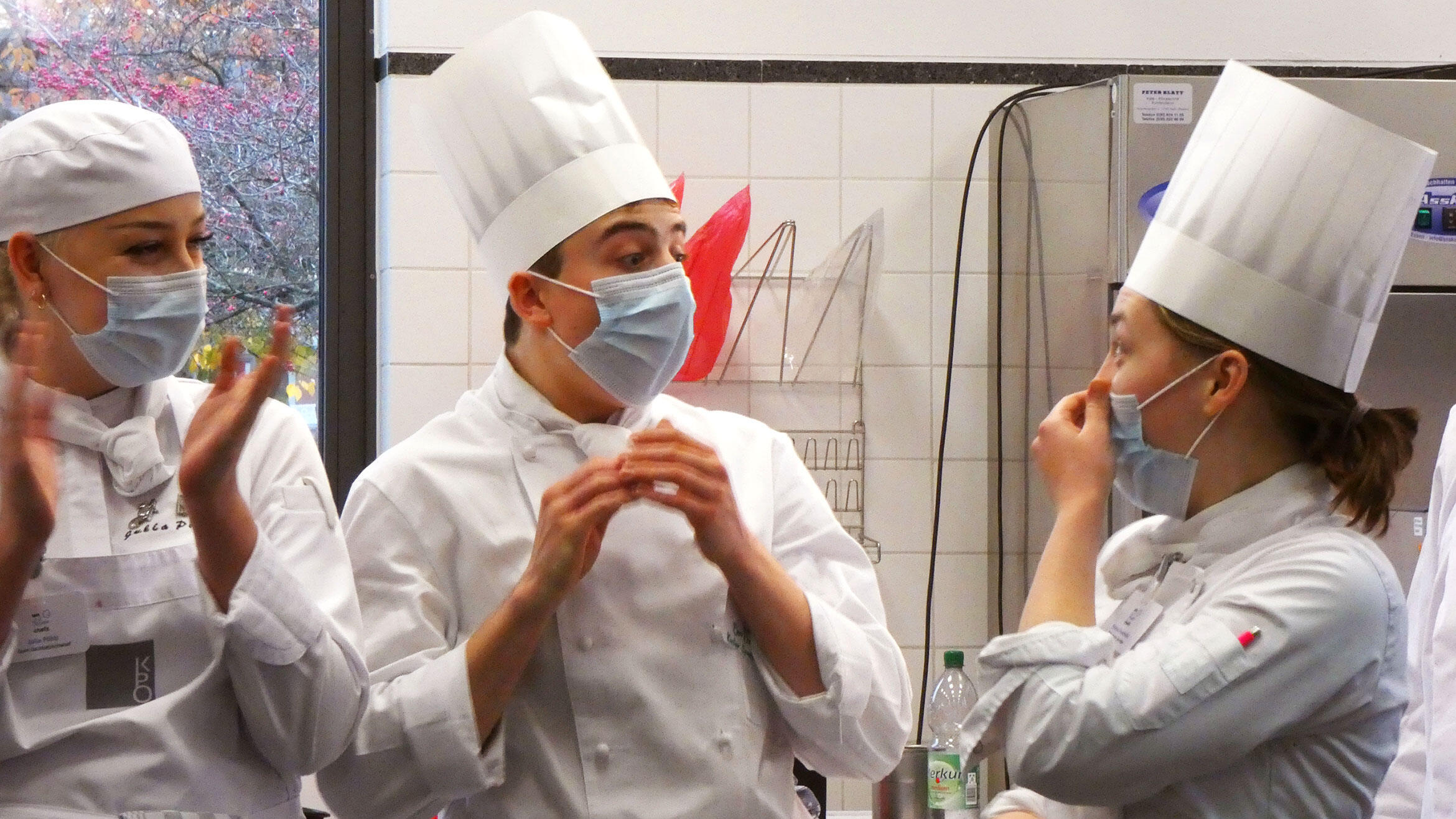 zwei junge Köchinnen und ein Koch sind erstaunt über den Gewinn des Wettbewerb