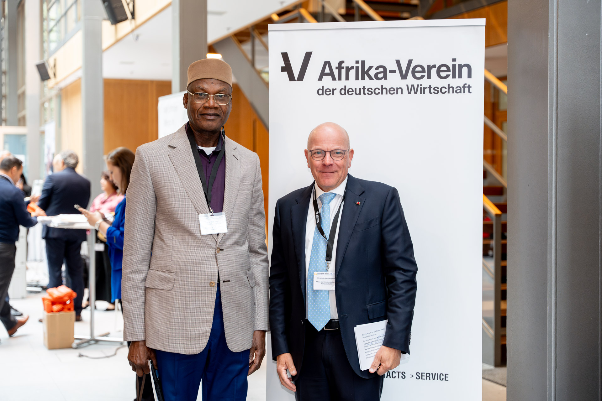 two men stand next to each other and smile into the camera