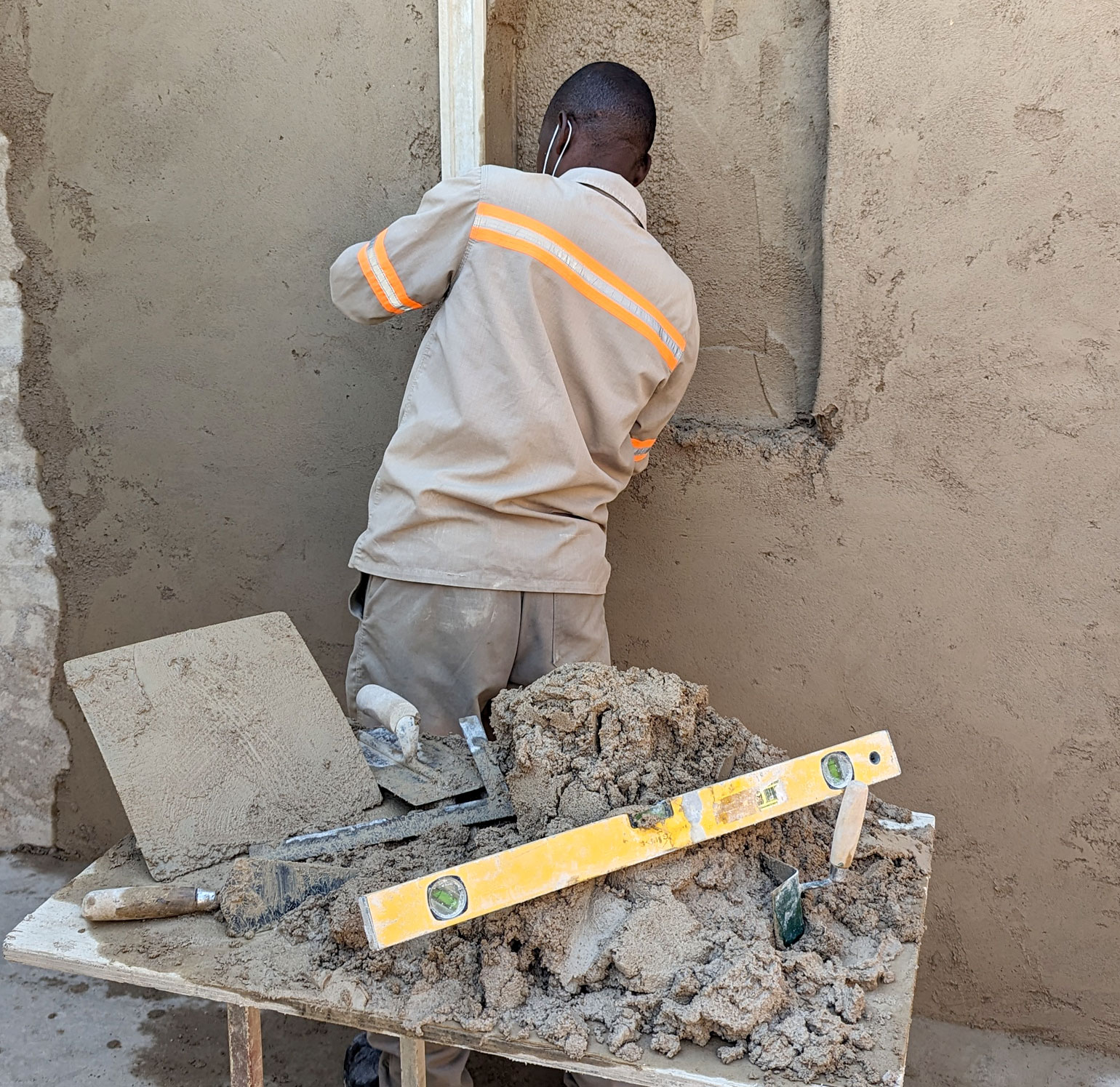 man measuring a recess in a plastered wall