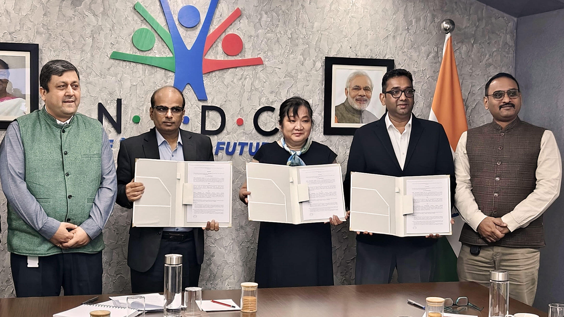 Signatories of the declaration of intent stand next to each other and hold the declaration up to the camera