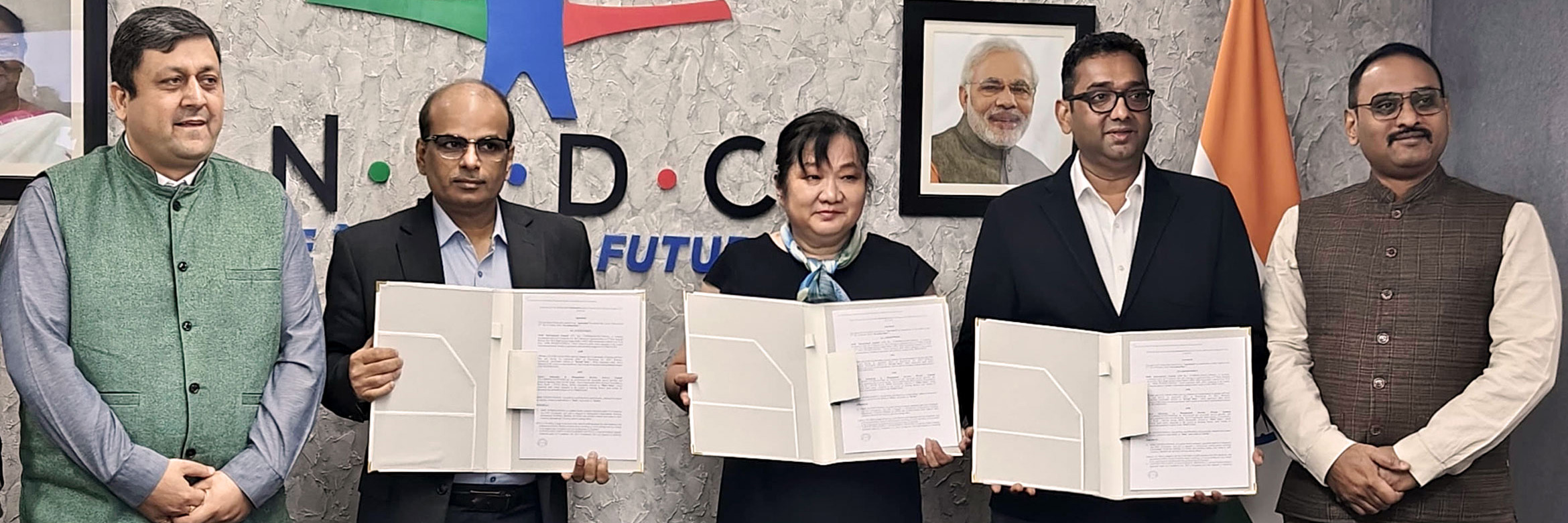 Signatories of the declaration of intent stand next to each other and hold the declaration up to the camera