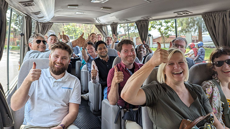 People on a bus raise their hands with their thumbs up